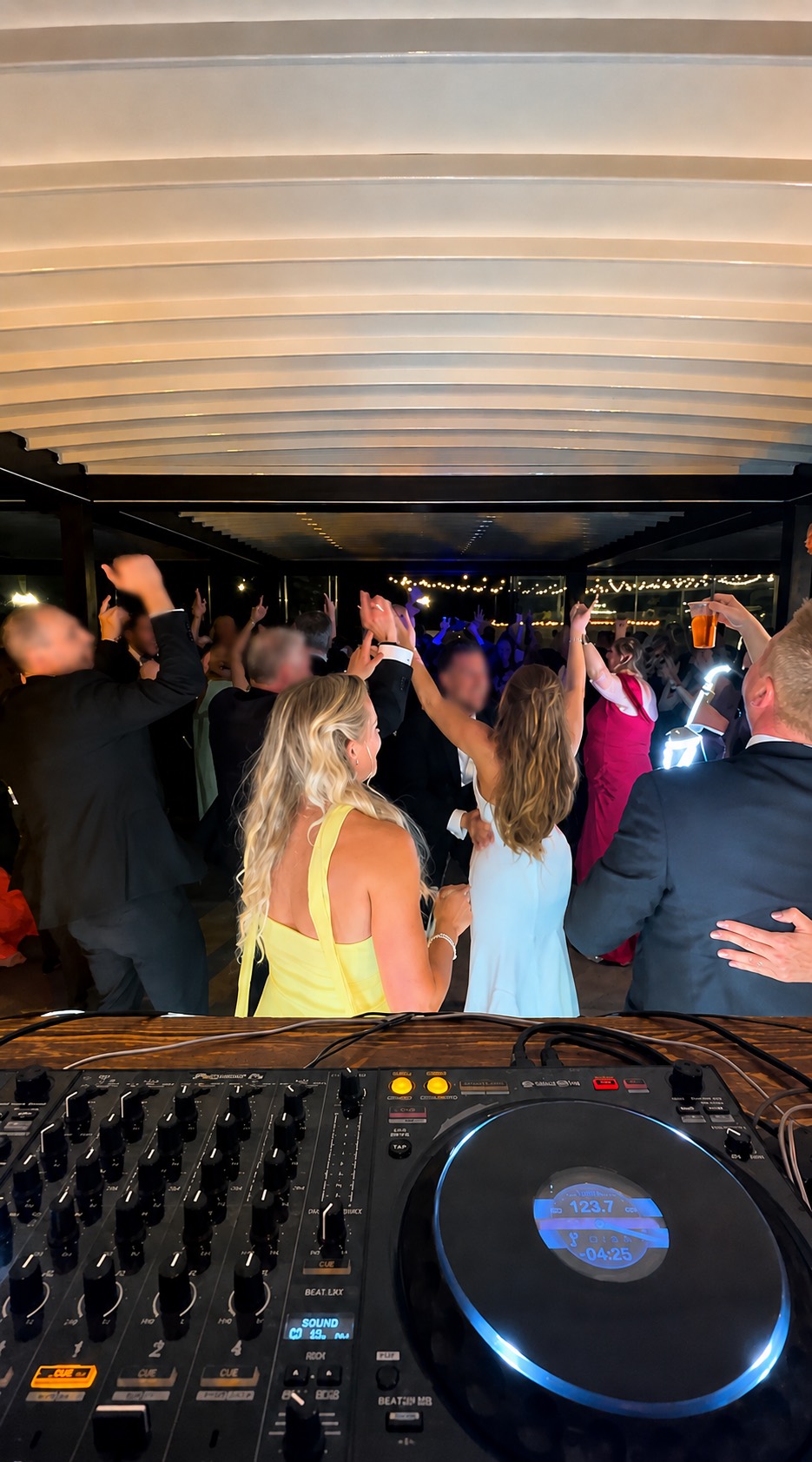 Wedding guests dancing behind a DJ booth at a Tuscany reception